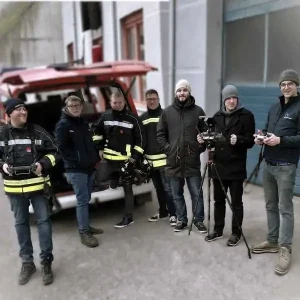 Schulungsteilnehmer BOS Drohnenschulung Flugpraxis mit FF-Auto im Hintergrund