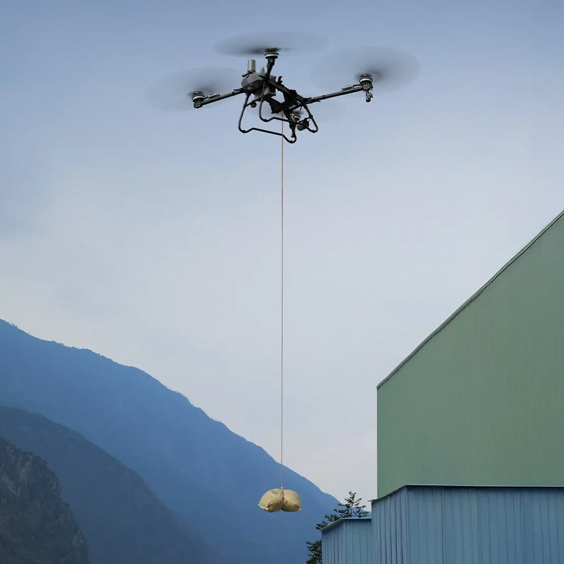 DJI T100 Drohne transportiert Packet mit Hebesystem Kit - Produktbild schräg